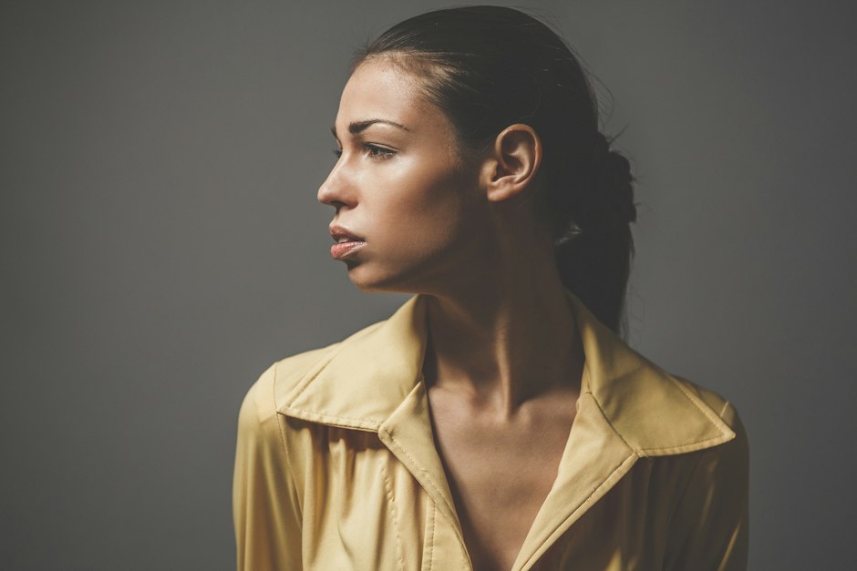 A woman in side profile against a grey background
