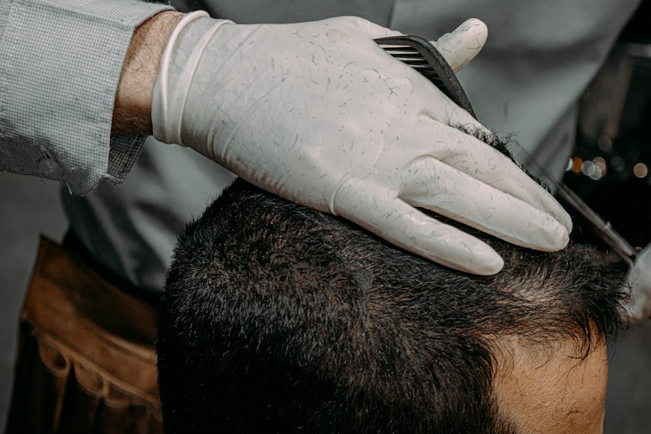 Gloved hands examining the hairline on a man's scalp